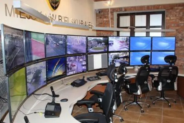 Zdjęcie przedstawiające stanowisko monitoringu miejskiego z wieloma ekranami i krzesłami.