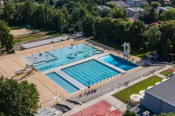 Zdjęcie przedstawiające kompleks odkrytych basenów przy ul. Marii Konopnickiej w Bielsku-Białej z brodzikiem, zjeżdżalniami i trybunami, widziany z lotu ptaka.