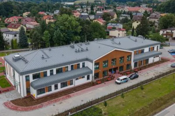 Zdjęcie przedstawiające nowoczesny budynek przedszkola przy ul. Janowickiej z parkingiem, widziany z lotu ptaka.