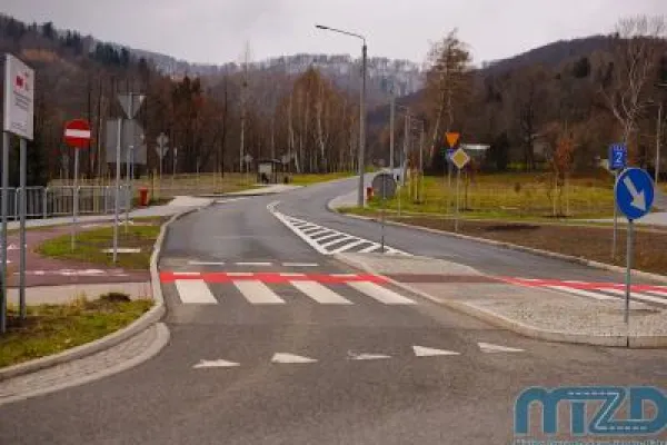 Zdjęcie przedstawiające nowo wybudowaną drogę z przejściem dla pieszych i znakami drogowymi w górskim otoczeniu.