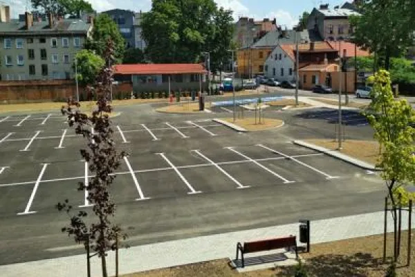 Zdjęcie przedstawiające pusty, nowo wybudowany parking z wyznaczonymi miejscami postojowymi.