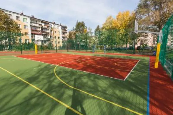 Zdjęcie przedstawiające boisko sportowe i zabudowę mieszkaniową w tle.