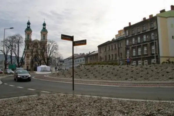 Zdjęcie przedstawiające rondo w centrum miasta z kościołem w tle i zabudową mieszkalną.