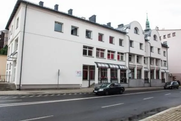 Zdjęcie przedstawiające budynek Urzędu Miejskiego w Bielsku-Białej przy ul. Stanisława Stojałowskiego 32 o białej elewacji od strony ulicy. 