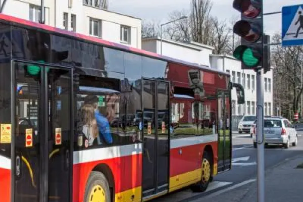 Zdjęcie przedstawiające autobus miejski przejeżdżający na zielonym świetle.