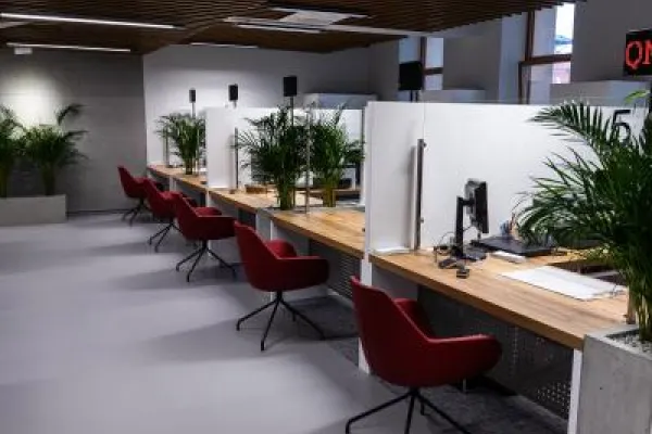 Zdjęcie przedstawiające nowoczesne stanowiska obsługi klienta z komputerami i czerwonymi krzesłami.