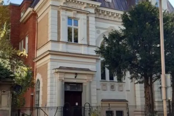 Zdjęcie przedstawiające zabytkową kamienicę z ozdobną fasadą i stromym dachem.